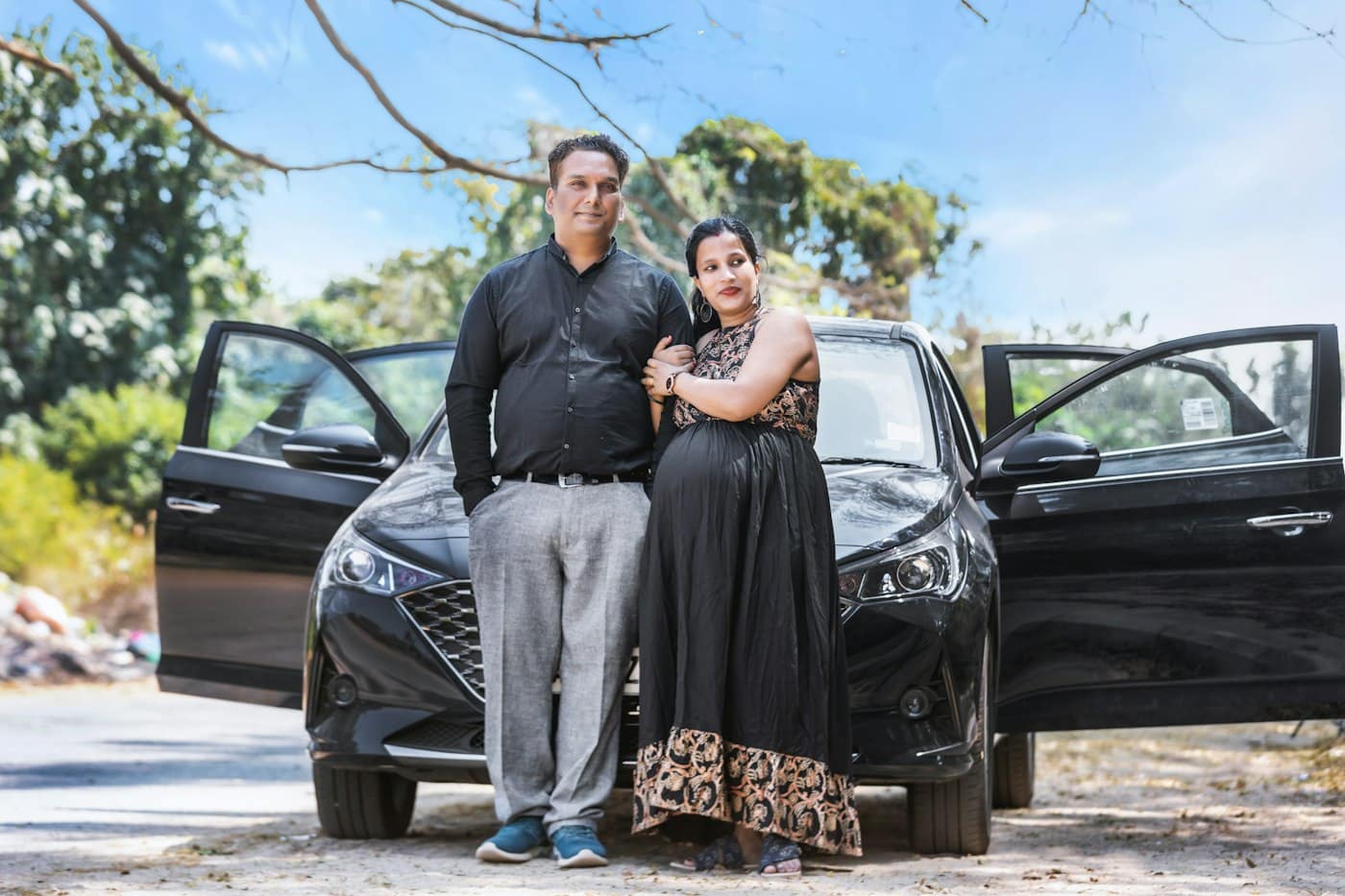A couple standing proudly beside their car